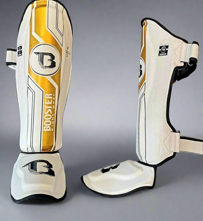 Booster V9 Kickboks Set Wit/Goud – wit-gouden BSG Pro V9 scheenbeschermers, voorzijde en zijaanzicht met sluitingen